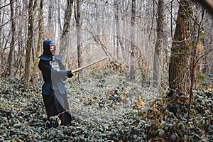 Man practicing kendo with shinai bamboo sword on forest background. Place for text or advertising