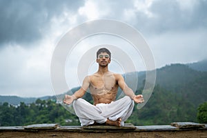 A man practicing meditation and zen energy yoga in mountains.Man doing fitness exercise sport outdoors in morning. Healthy
