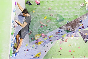 Man practicing rock climbing on artificial wall indoors. Active