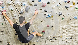 Man practicing rock climbing on artificial wall indoors. Active