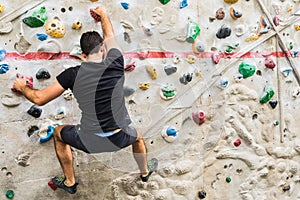 Man practicing rock climbing on artificial wall indoors. Active lifestyle and bouldering concept