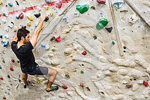 Man practicing rock climbing on artificial wall indoors. Active lifestyle and bouldering concept