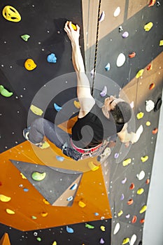 Man practicing rock-climbing on rock wall indoors