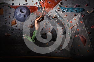 Man practicing rock-climbing on a rock wall indoors