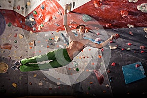 Man practicing rock-climbing on a rock wall indoors