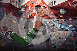 Man practicing rock-climbing on a rock wall indoors