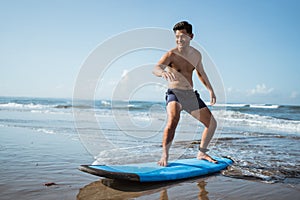 a man practicing surfing by standing on a surfboard on the sand