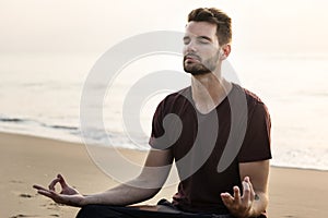 Man practicing yoga on the beach