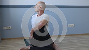 Man practicing yoga and sitting in twist pose at home