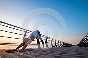 Man practicing yoga at sunset and doing dog face down