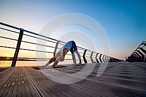 Man practicing yoga at sunset and doing dog face down