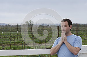 Man praying in front of farmland alone.