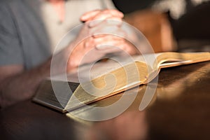 Man praying hands on a Bible