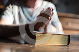 Man praying hands on a Bible