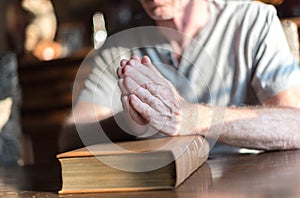 Man praying hands on a Bible