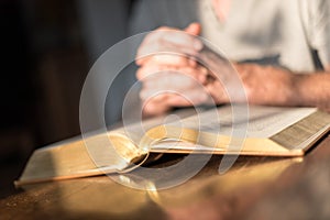 Man praying hands on a Bible