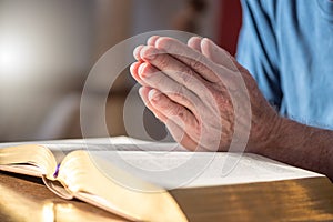 Man praying with his hands over the bible