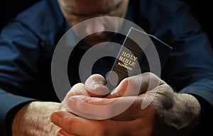 A Man praying holding a Bible.