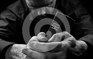 A Man praying holding a Bible.