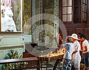 Man praying holding candles up to our lady in church in Cuba