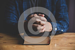 A Man praying holding a Holy Bible.