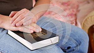 Man praying holding a Holy Bible at home