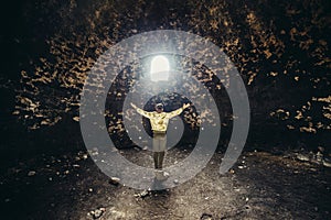 Man praying and hoping with arms raised up to the mystery light. Religion miracle concept photo