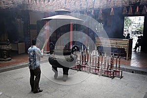 Man praying in incense smoke filled temple in Ho Chi Minh City