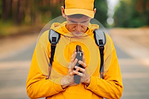 Man praying outdoors while holding a Bible in his hands. A man in a yellow sweater and a cap holds a Bible in his hands