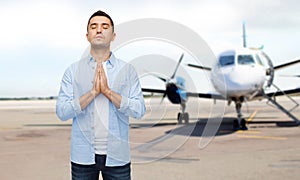 Man praying over airplane on runway background