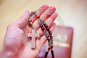 Man is praying: Rosary in the hands, holy bible in the background