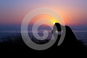 Man Praying by the Sea at Sunset photo