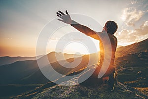 Man praying at sunset mountains raised hands