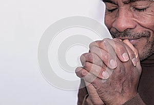 Man praying to god with hands together Caribbean man praying with grey background stock photo