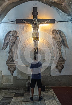 Man prays in front of Jesus on the Cross at San Augustin church, Manila Philippines