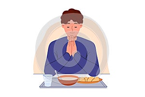 Man prays sitting at table with food, observing christian tradition and expressing gratitude to god