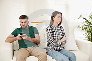 Man preferring smartphone over his girlfriend at home. Relationship problems photo