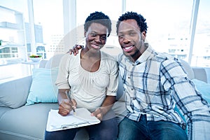 Man with pregnant wife writing on notepad