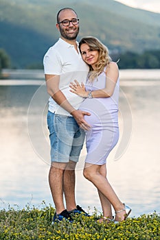 Man with pregnant woman by lake