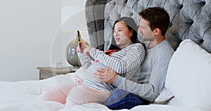 Man and pregnant woman looking at sonography in bedroom 4k