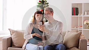 Man and pregnant woman taking selfie at christmas