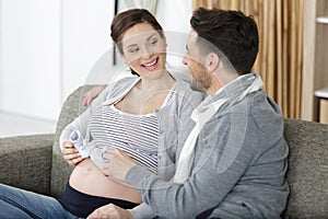 man and pregnant women holding baby shoes