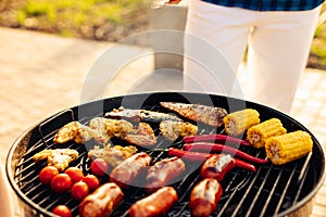 Man prepares a barbecue for friends, happy friends make a barbecue outdoors at sunset, A man roasts meat on the grill