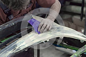 A man prepares a car body element for painting after an accident