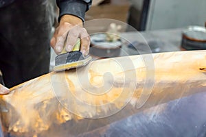 A man prepares a car body element for painting after an accident