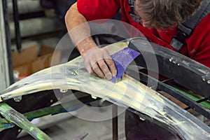 A man prepares a car body element for painting after an accident