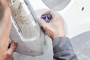 A man prepares a car body element for painting after an accident with the help of abrasive paper in a car repair shop. Recovery