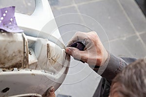 A man prepares a car body element for painting after an accident with the help of abrasive paper in a car repair shop. Recovery