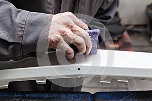 A man prepares a car body element for painting after an accident with the help of abrasive paper in a car repair shop. Recovery