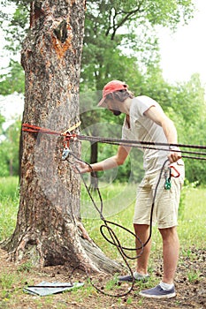 Man prepares the equipment fixes secures the rope to the tree
